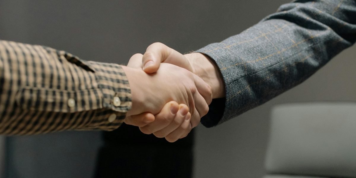 Two business professionals shaking hands, symbolizing trust and a verified partnership in real estate transactions.